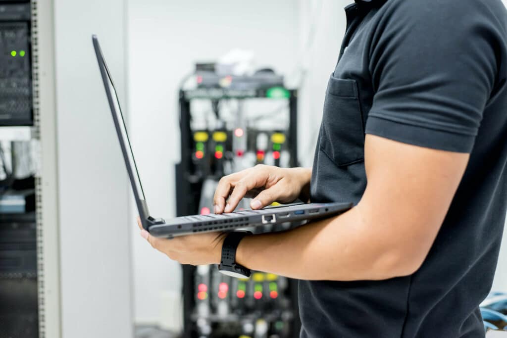 Someone holding a laptop in a server room working on executing updates using Right Click Tools.