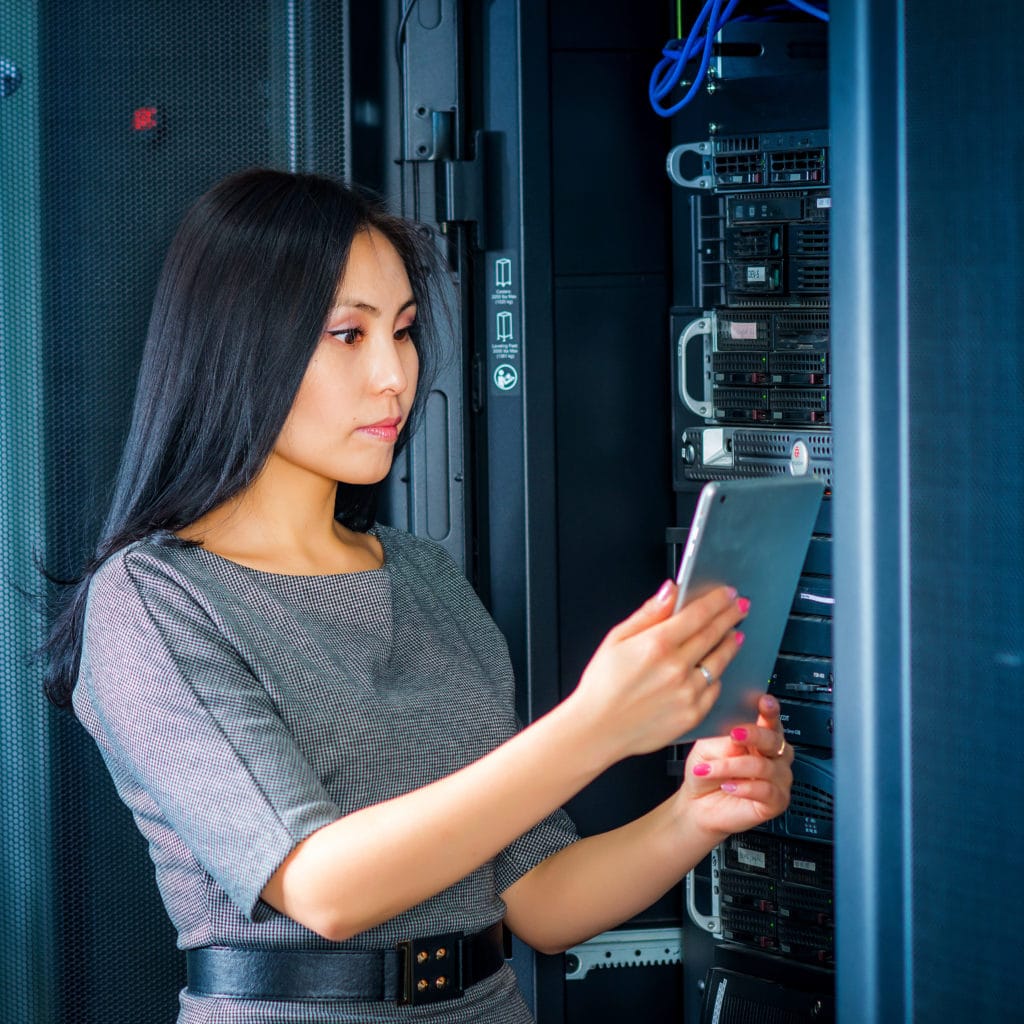 Young engineer businesswoman with tablet in network server room.