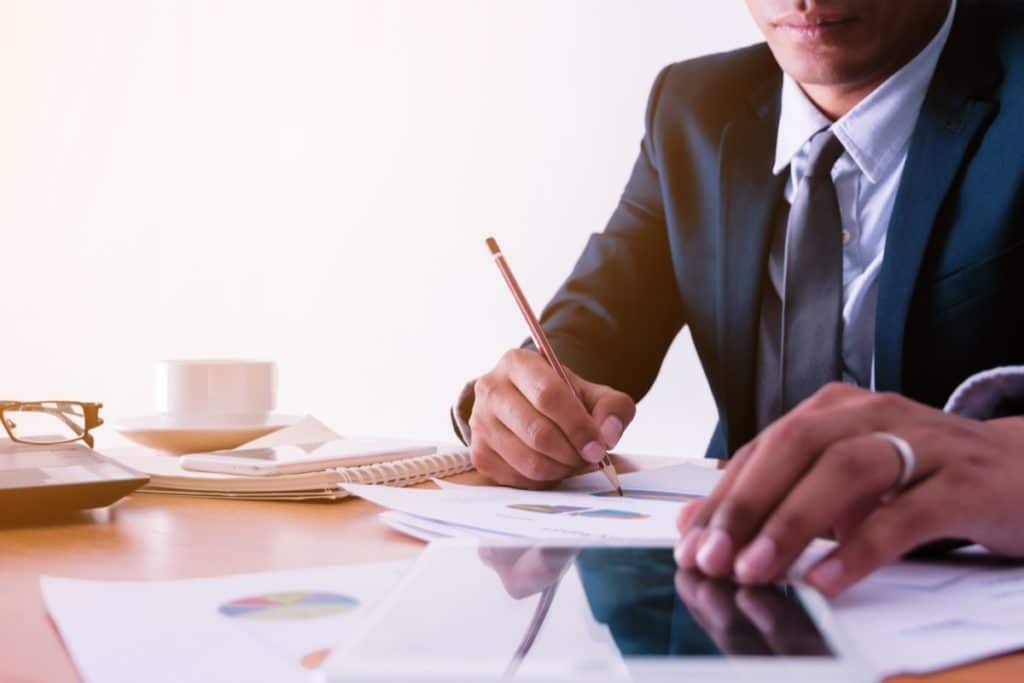 Man shown at his desk manually tracking data with a pencil and paper.