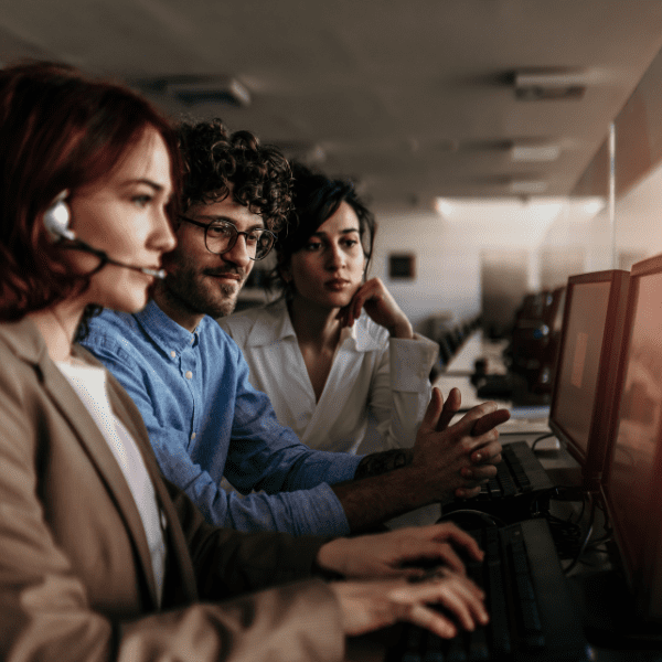 Help desk associates working together while one of them is wearing a headphone set. 