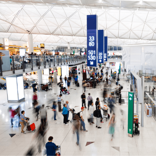 A airport terminal showing travels with their bags looking at the monitors of arrival and departure times.