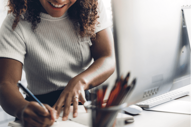 Woman filling out paperwork next to her computer that is supported by Liquit